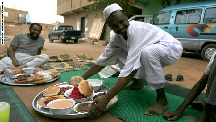 مردی در حال قرار دادن سینی غذا بر سر سفره افطار در شرق خارطوم پایتخت سودان