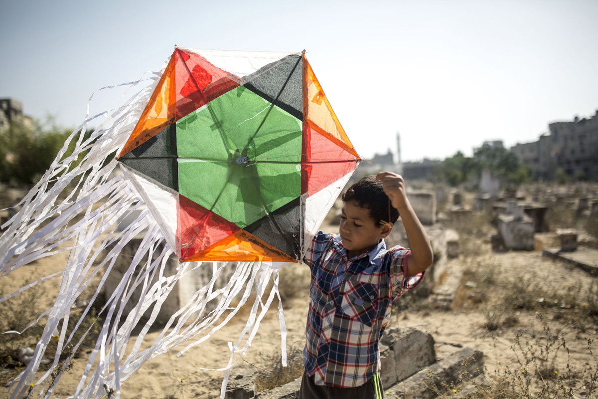 یک کودک در گورستان اردوگاه پناهندگان جابالیا در نوار غزه بادبادک بازی می‌کند