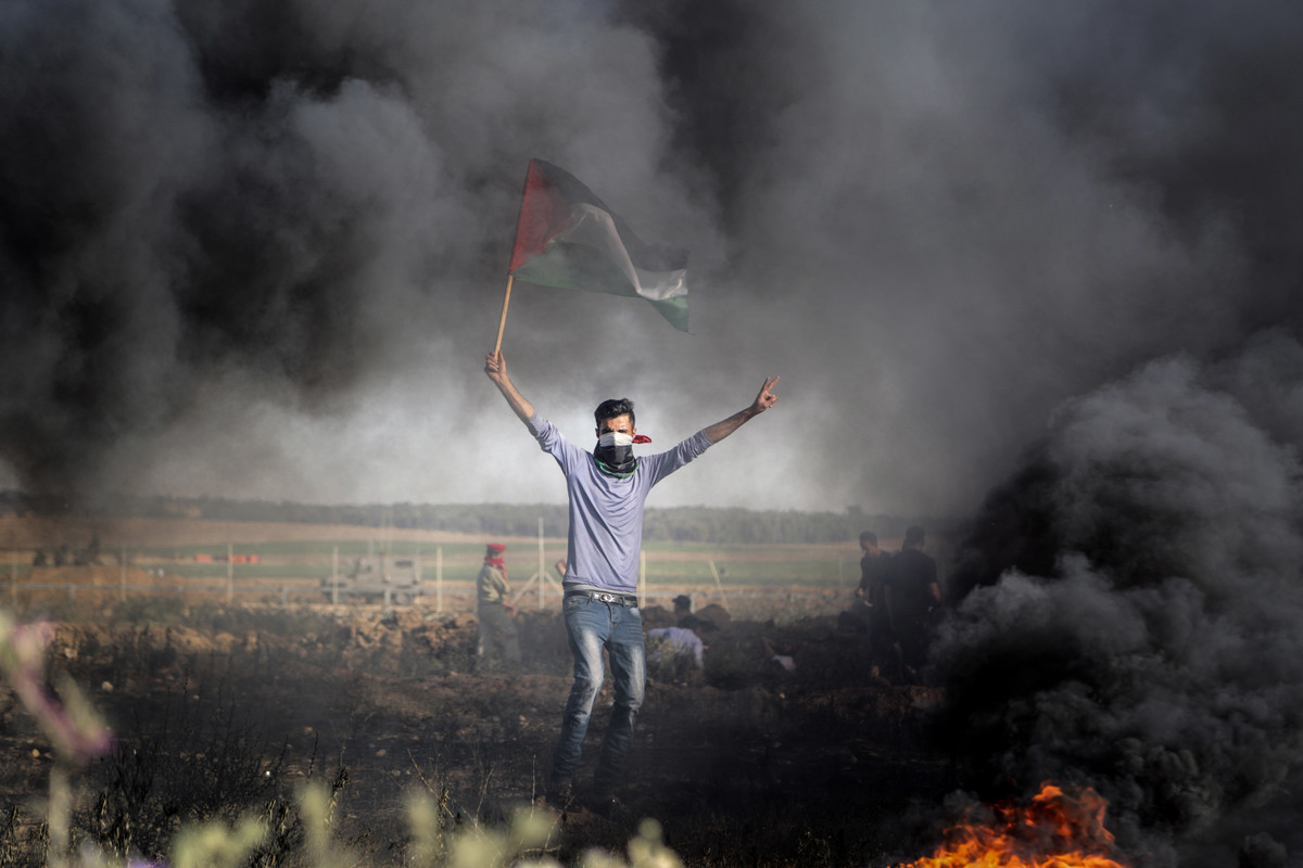 یک تظاهرکننده پرچم فلسطین را در راهپیمایی علیه نیروهای اشغالگر قدس در نزدیکی در برابر محاصره در نزدیکی حصار مرزی