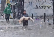 فیلم | صحنه‌ای غم انگیز از حمل جسد کودک غزه‌ای زیر باران شدید