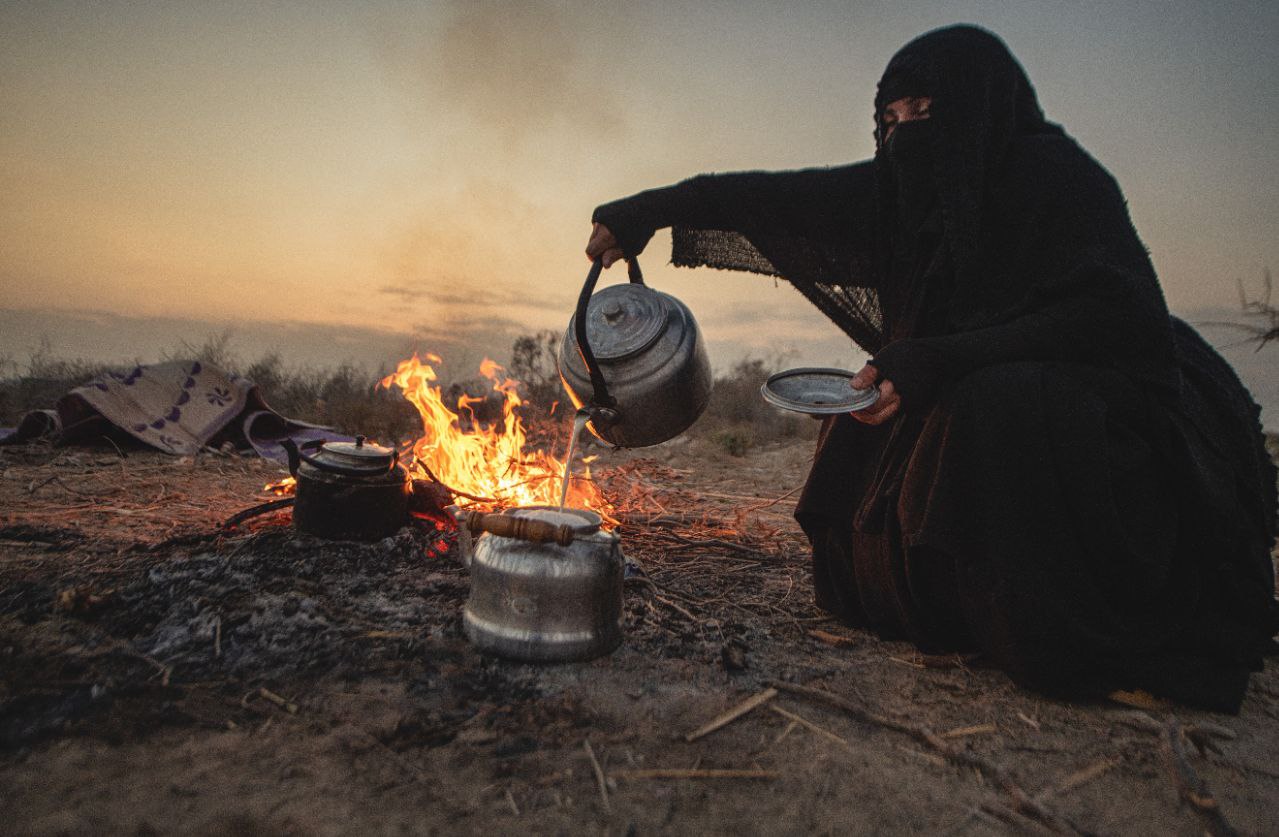 Senior Lady serves Arbaeen pilgrims in a barren land