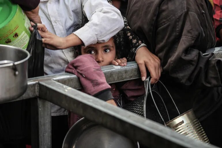 کودکان در اردوگاه نصیرات در مرکز نوار غزه منتظر دریافت غذای گرم توزیع شده توسط خیریه‌ها هستند.