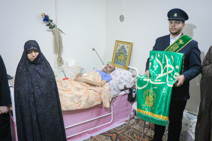 عیادت از جانباز قطع نخاعی جنگ رمضان به مناسبت روز ولادت حضرت رضا علیه السلام با حضور خادمان و پرچم متبرک حضرت معصومه سلام الله علیها