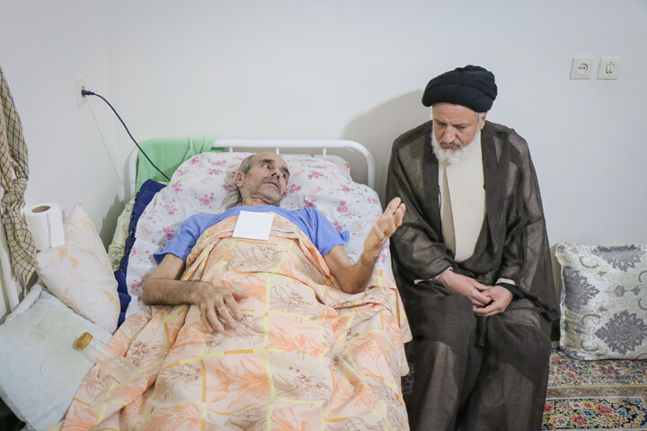 عیادت از جانباز قطع نخاعی جنگ رمضان به مناسبت روز ولادت حضرت رضا علیه السلام با حضور خادمان و پرچم متبرک حضرت معصومه سلام الله علیها